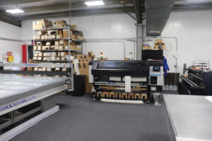 Production room with printers, cutting tables, and sign-making equipment.